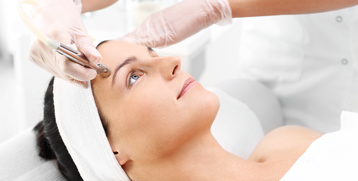 Esthetician performing a microdermabrasion treatment on a patient's face