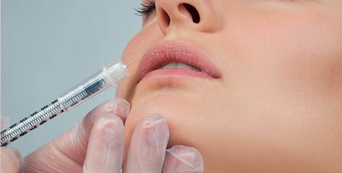 Provider injecting Restylane dermal filler into a patient's lips